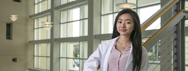 female FAU student poses in white lab coat