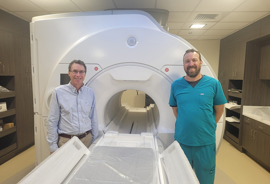Two medical personnel standing in front of MRI machine