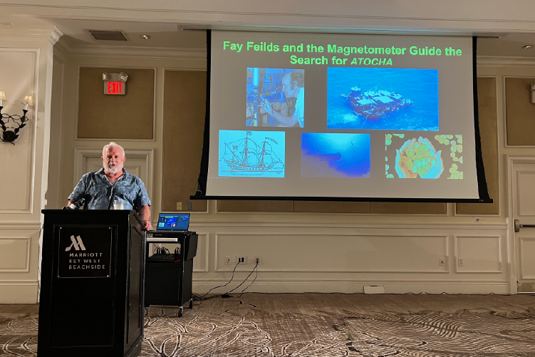 Brian Lapointe, Ph.D., at podium next to large screen displaying ocean-themed images