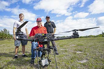 three men holding a drone