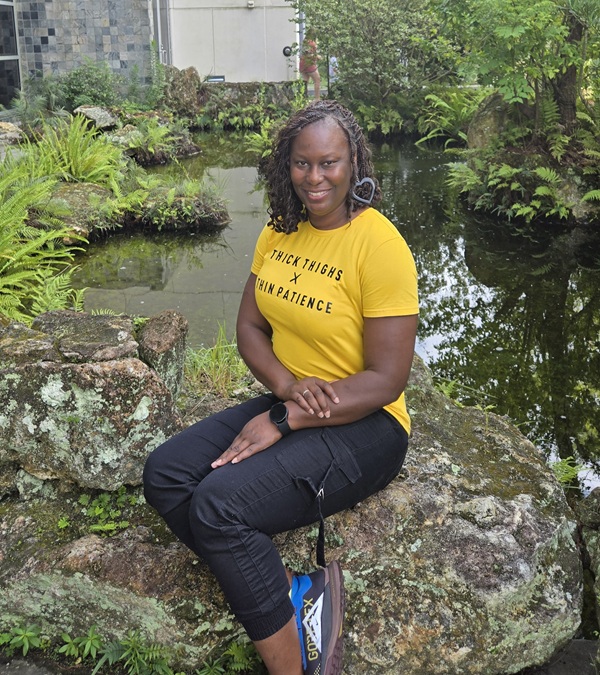 woman sitting on rick in natural area wearing yellow shirt and black pants