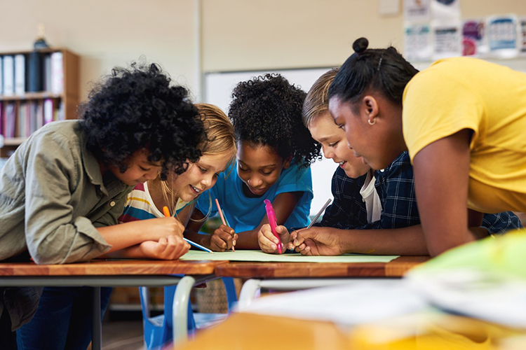 students around desk in classroom setting
