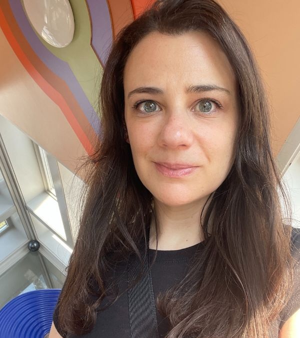 woman with long dark hair stnading in front of pastel geometric background