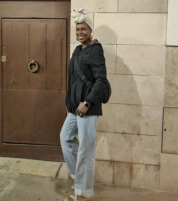 woman standing in front of stone building next to brown door