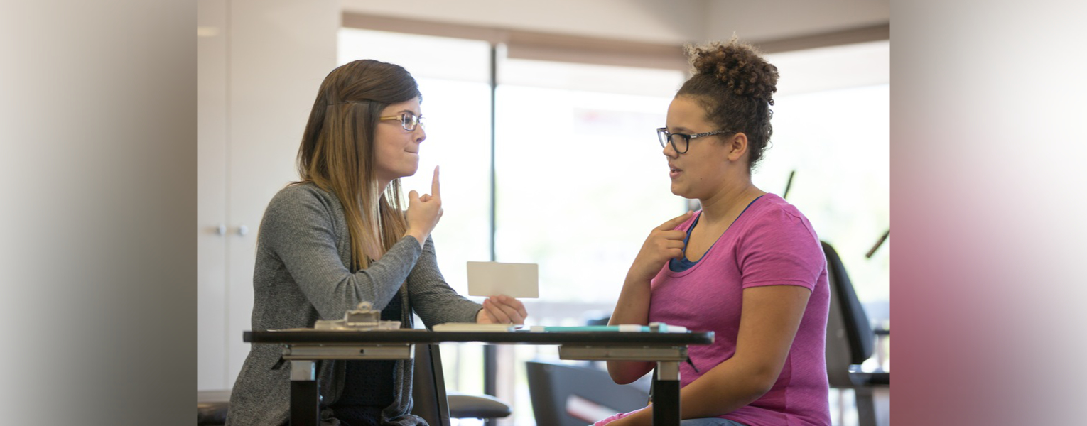 two women sitting at table in conversation