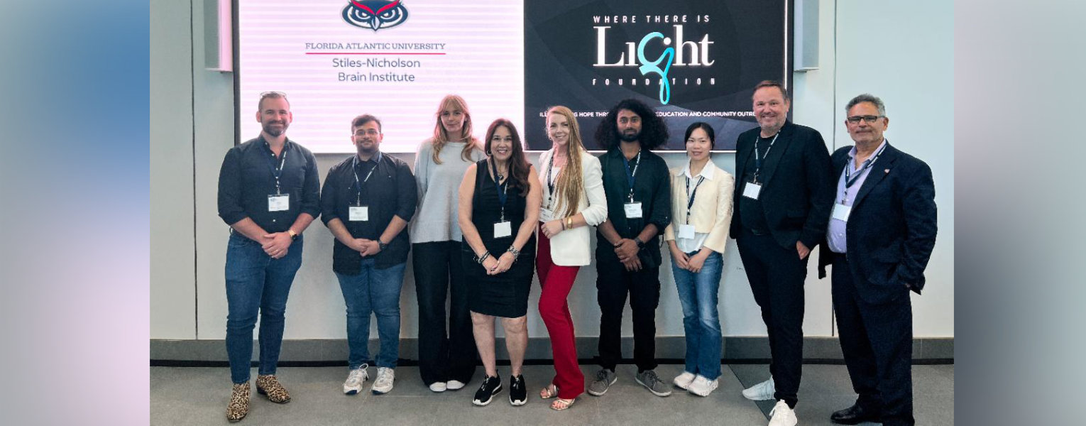 group of people standing in front of screen with words, 'Where there is light foundation' and FAU owlhead logo