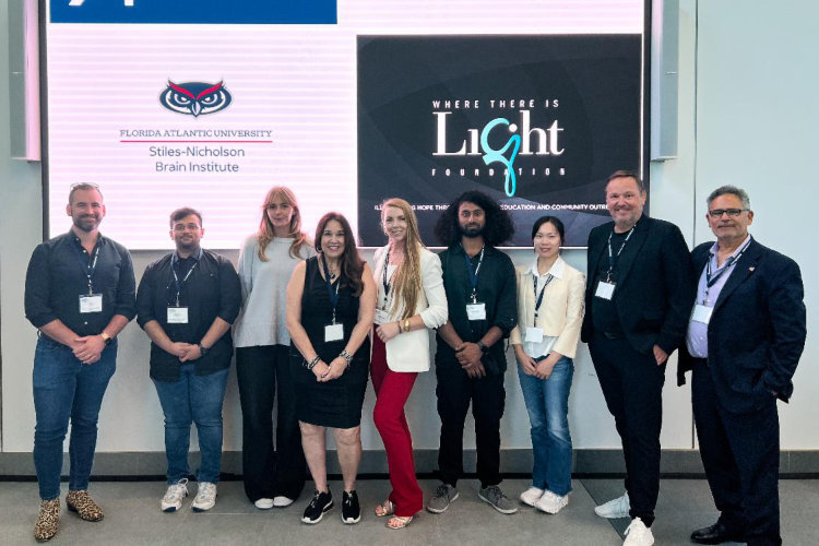 group of people standing in front of screen with words, 'Where there is light foundation' and FAU owlhead logo