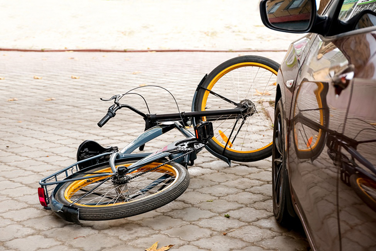 bicycle laying in street next to vehicle
