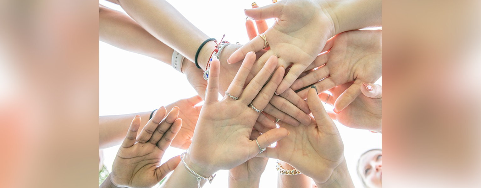 Group of hands piled on top of each other (Photo by Alex Dolce)