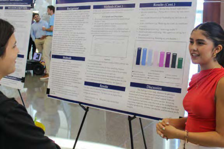 Two people standing by large graphic on easel