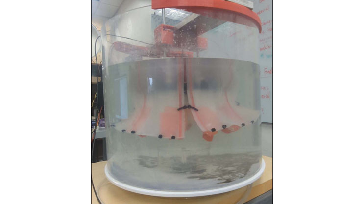 Slide 8: Full-frame photo of the soft robotic jellyfish submerged in the cylindrical test tank, with its bell segments extended and sensor markers visible along the base.