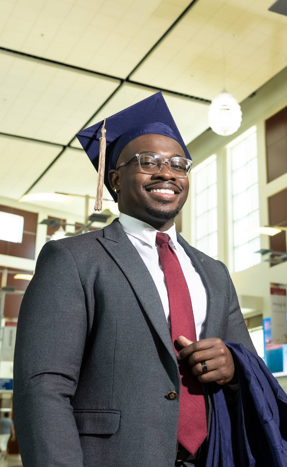 man wearing suit and graduation cap, smiling