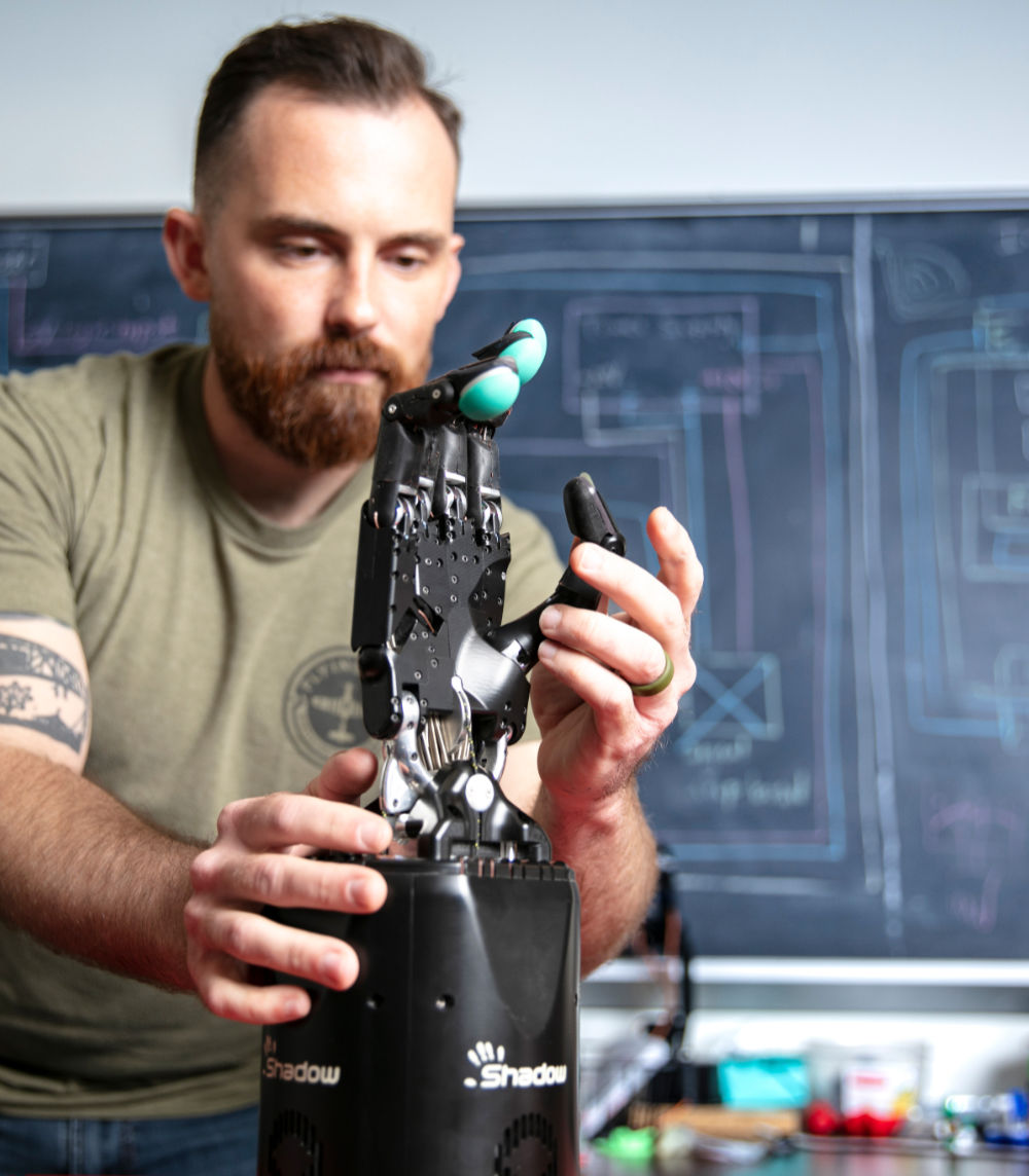 man observing robotic hand in classroom setting