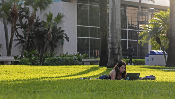 Student studying with laptop on lawn in front of Administration Building