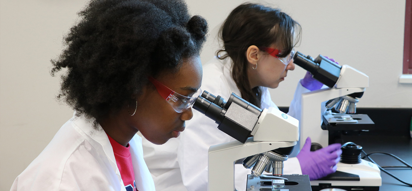 two female students in the lab looking through a microscope