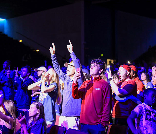 Crowd of students in the auditorium at watch party cheering