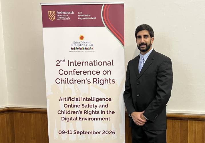 Dr. Hinduja standing next to banner for 2nd International Conference on Children's Rights