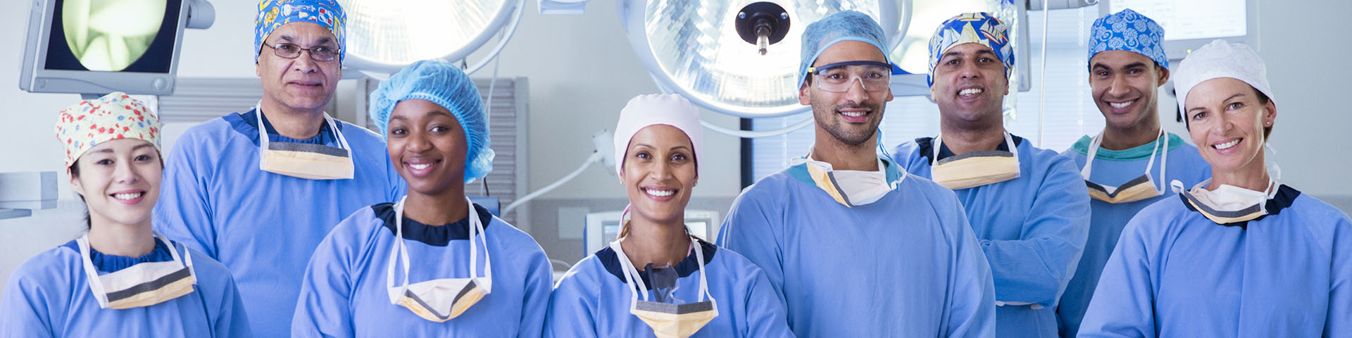 Group of people in operating room wearing scrubs smiling