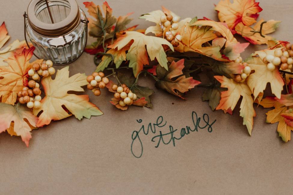 give thanks written on a table with leaves