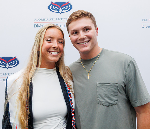 Student posing with military graduation sash in front of a Military background