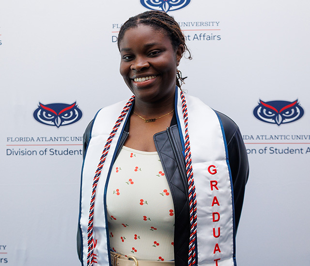 Student posing with military graduation sash in front of a Military background