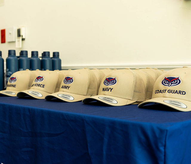 Promotional Florida Atlantic hats and water bottles sitting on a table