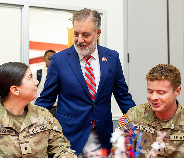 President Hasner talking with two veterans in uniform at a table