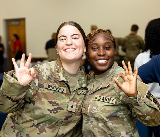 two Veteran student in uniform throwing up owl fingers