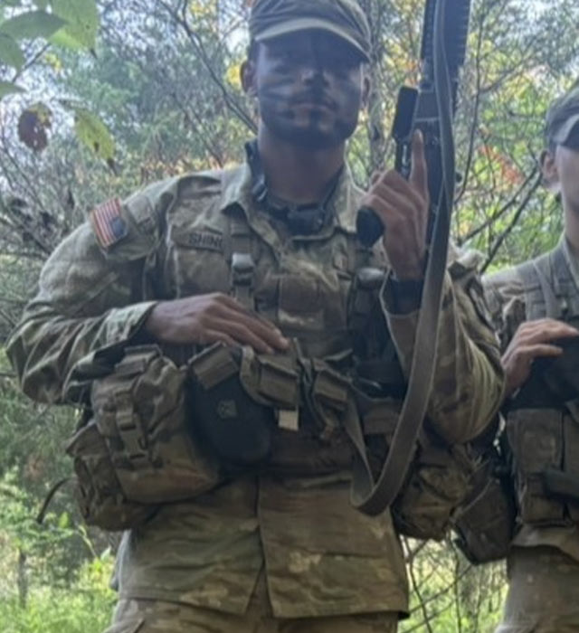 student dressed in army fatigues holding his weapon