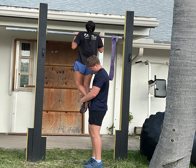 Student doing pullups at the MVSS Challenge getting assistance from another student